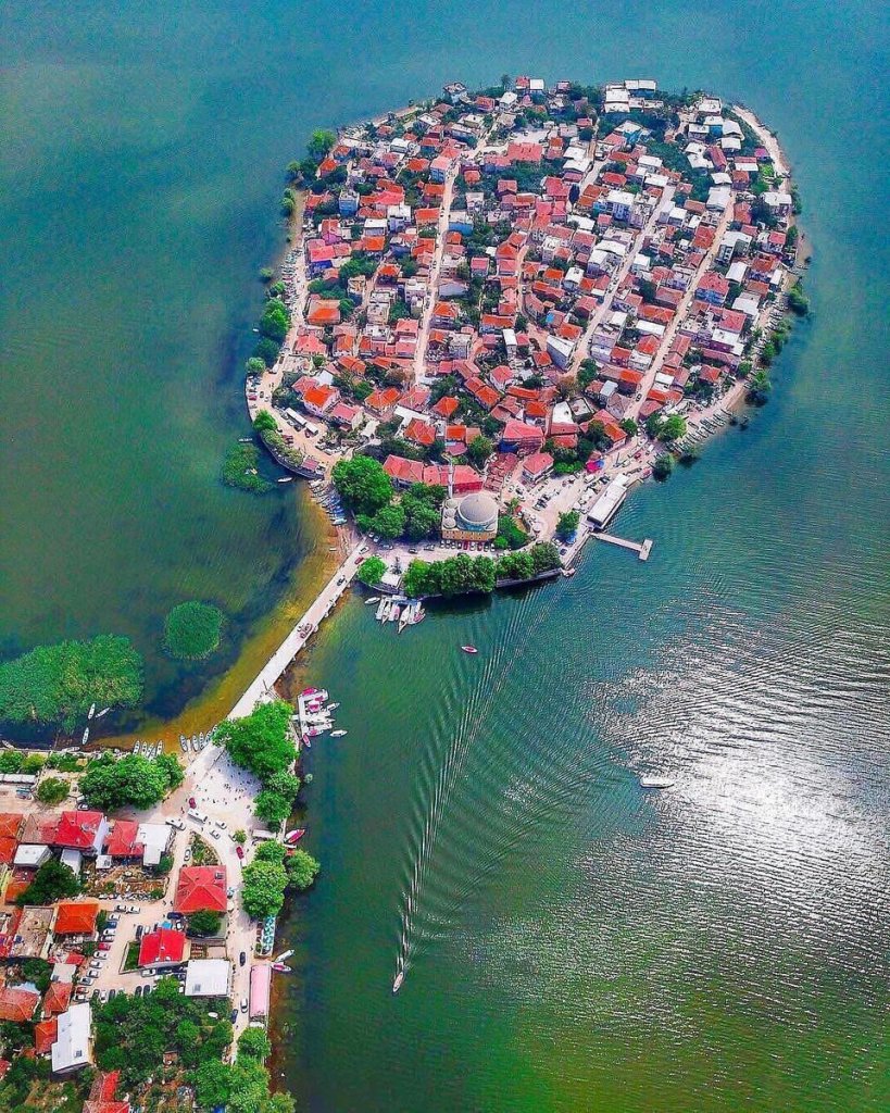 Hava görüntüsüyle çekilmiş, suyla çevrili bir ada üzerindeki yerleşim alanı.