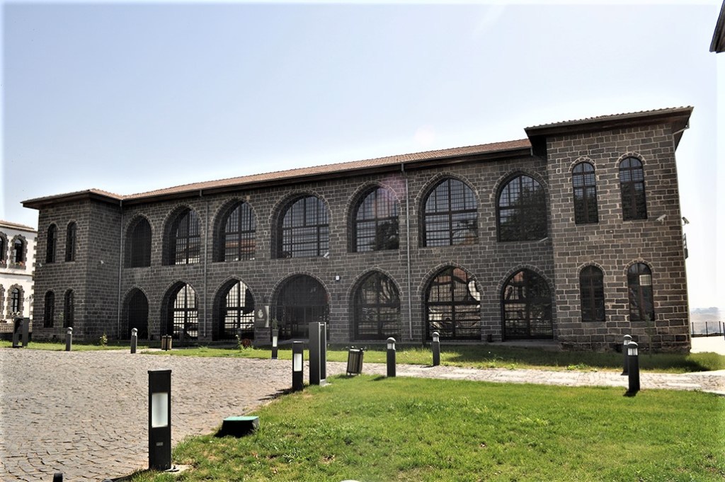 Tarihi taş yapıya sahip, geniş pencereli iki katlı bir bina.