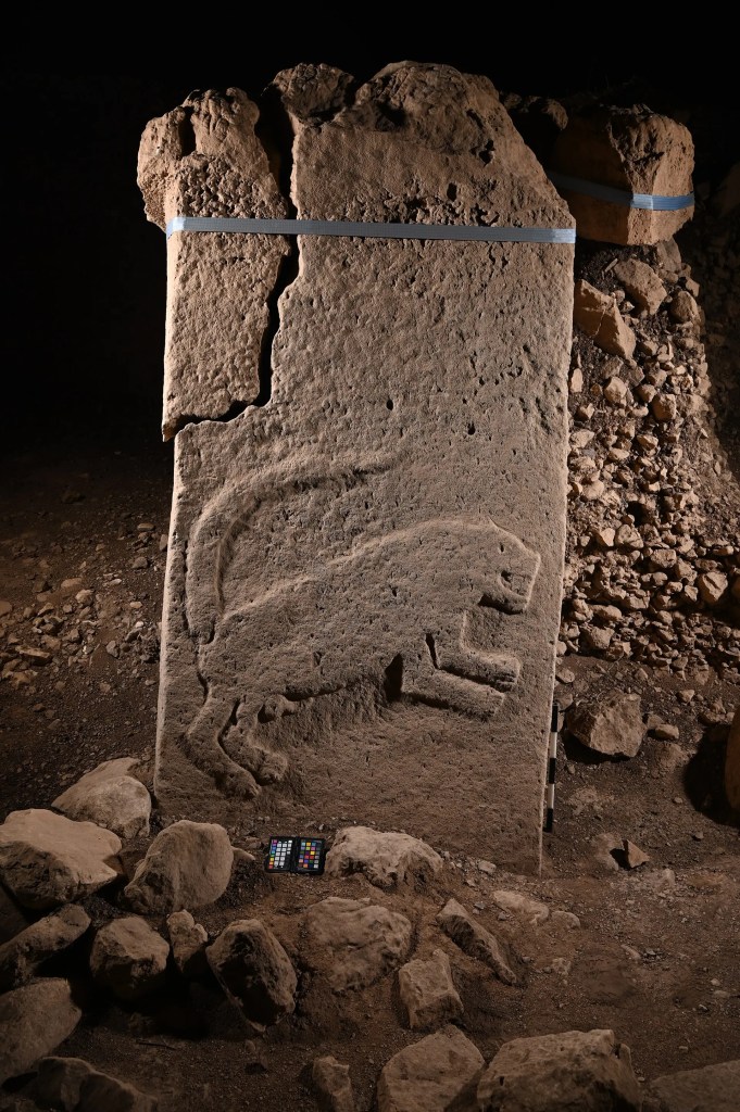 Göbeklitepe'de bulunan, üzerine aslan figürü oyulmuş büyük bir taş levha. Taşın etrafında ince taşlar ve düzensiz zemin görülmekte.